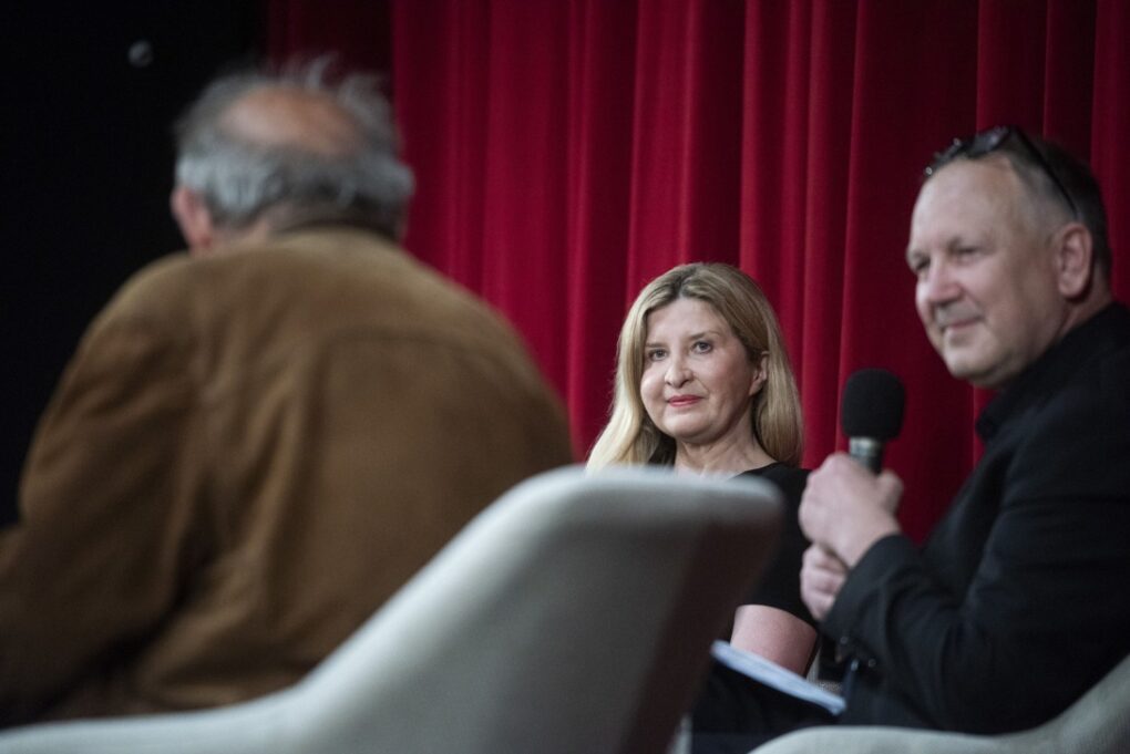 Prowadzący i uczestniczka debaty siedzą na scenie i prowadzą rozmowę przed publicznością (kliknięcie powiększy zdjęcie).