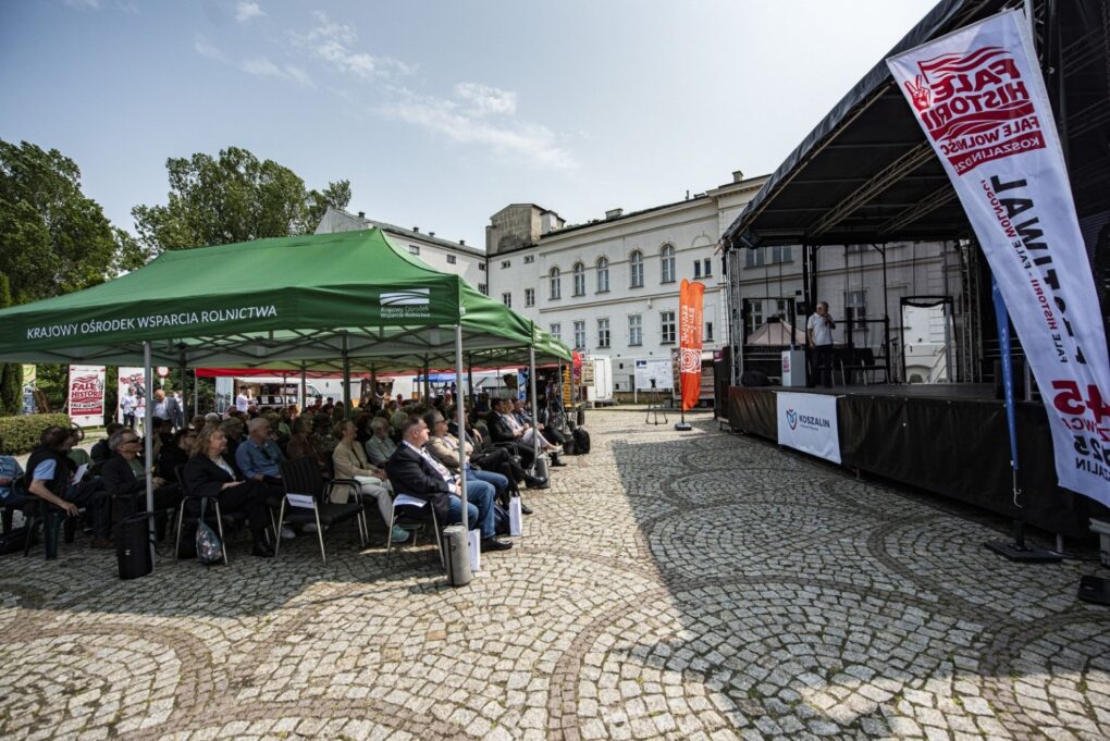 Widok na scenę i zgromadzoną publiczność siedzącą pod namiotami na dziedzińcu (kliknięcie powiększy zdjęcie).