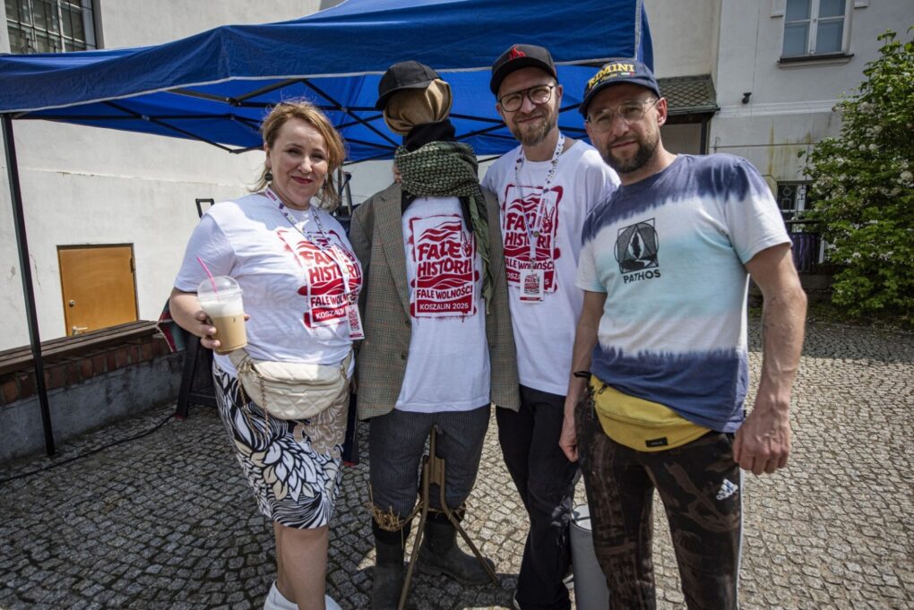 Grupa organizatorów wydarzenia w koszulkach z logo pozuje do zdjęcia na dziedzińcu (kliknięcie powiększy zdjęcie).