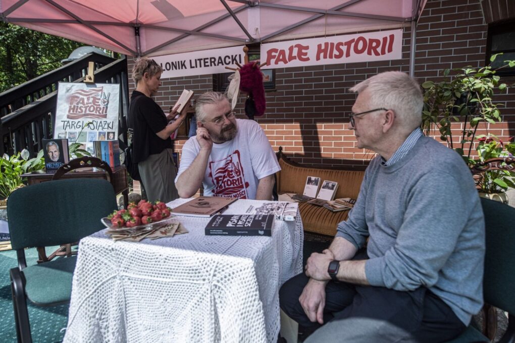 Dwie osoby siedzą przy stoliku, w ramach Targów Książki Historycznej i Regionalnej, i rozmawiają (kliknięcie powiększy zdjęcie).