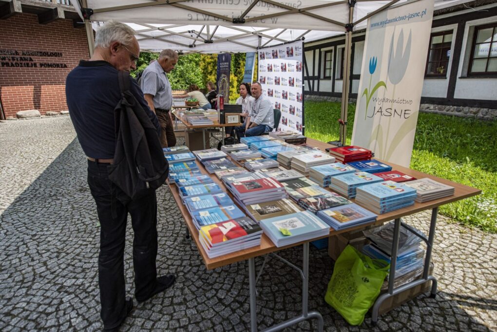Stoisko z książkami i publikacjami, przy którym odwiedzający przeglądają ofertę (kliknięcie powiększy zdjęcie).