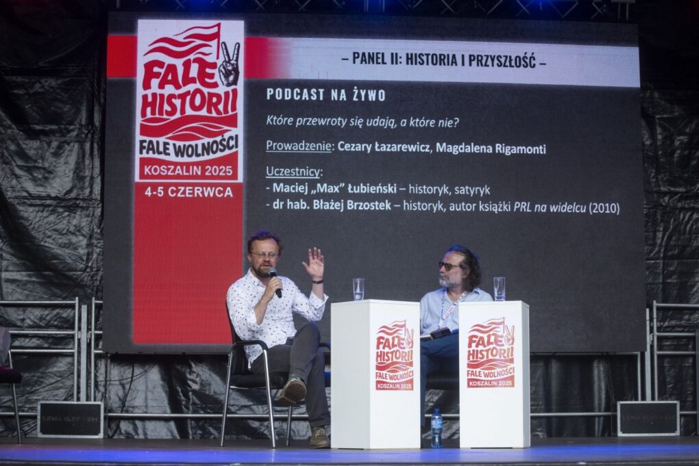 Dwóch prelegentów prowadzi rozmowę na scenie na tle ekranu z programem wydarzenia „Fale Historii” (kliknięcie powiększy zdjęcie).