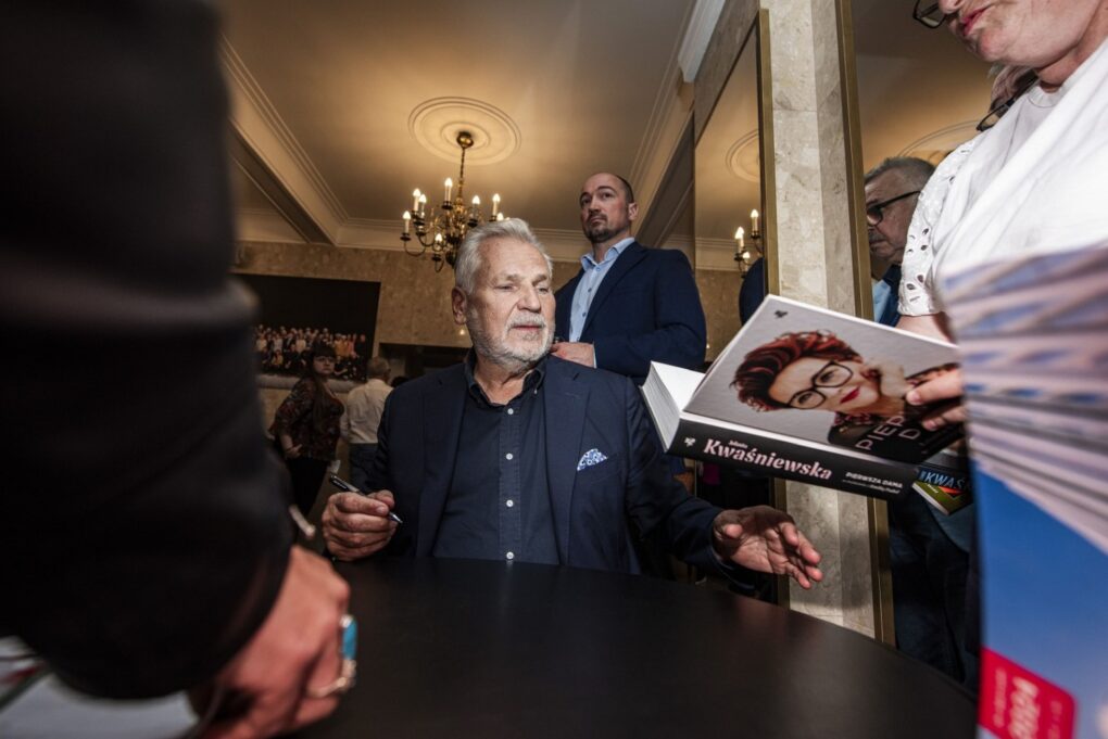 Aleksander Kwaśniewski rozmawia z uczestnikami i podpisuje książki przy stoliku (kliknięcie powiększy zdjęcie).