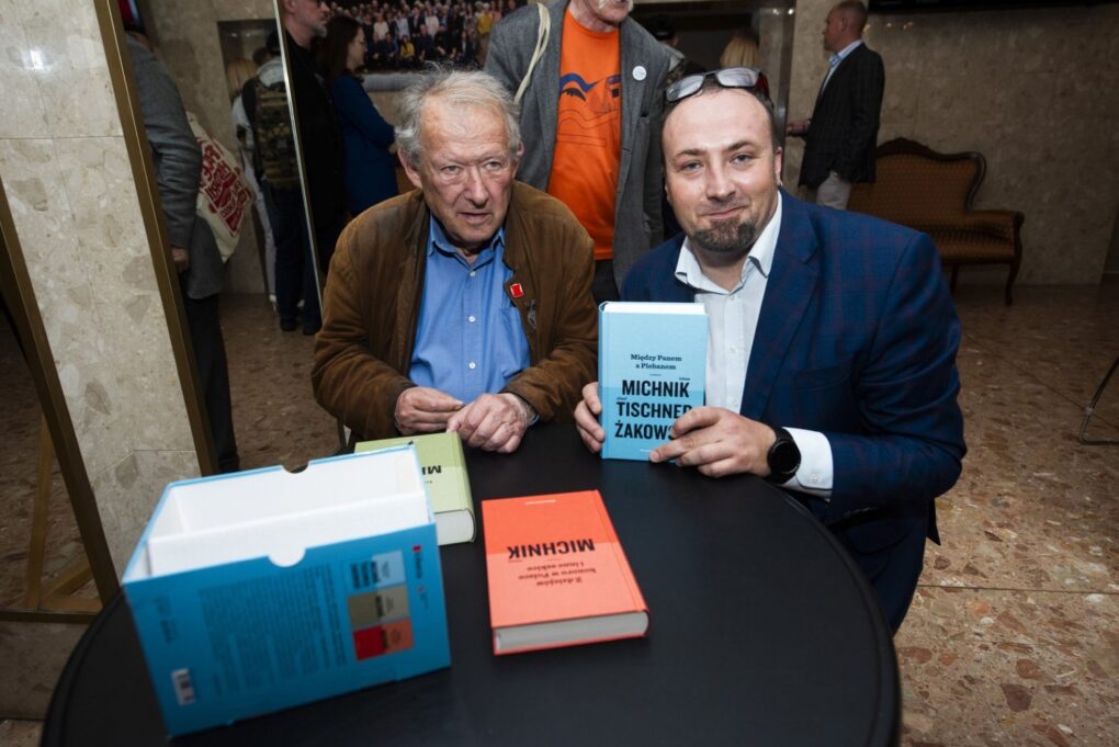 Dwóch mężczyzn prezentuje książkę podczas spotkania autorskiego (kliknięcie powiększy zdjęcie).