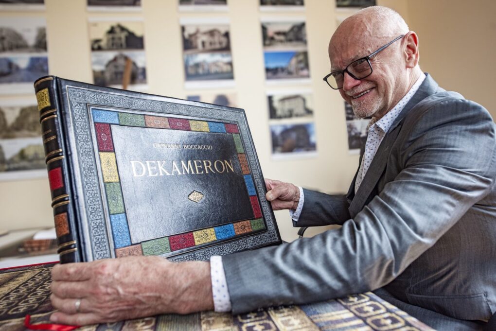 Mężczyzna prezentuje ozdobne wydanie książki „Dekameron” w przestrzeni wystawowej (kliknięcie powiększy zdjęcie).