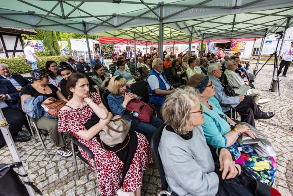 Publiczność siedzi pod namiotem i słucha programu wydarzenia „Fale Historii” (kliknięcie powiększy zdjęcie).