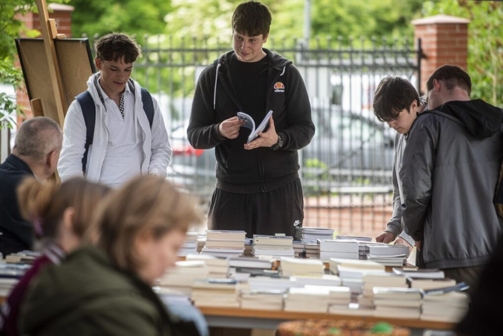 Młodzi uczestnicy przeglądają książki na stoisku z publikacjami (kliknięcie powiększy zdjęcie).