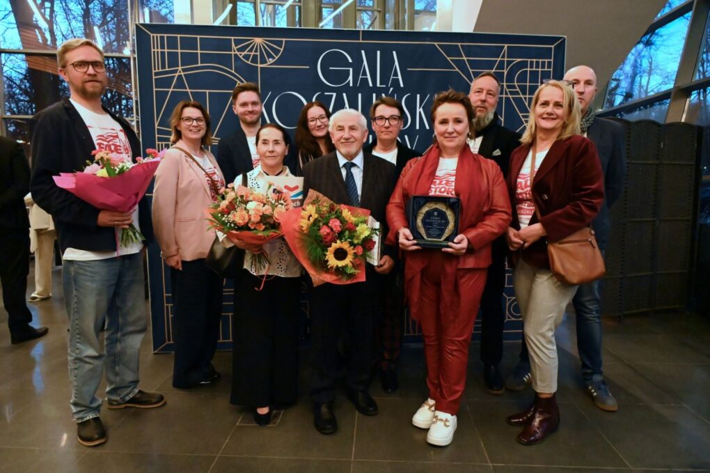 Pracownicy Muzeum w Koszalinie pozują do zdjęcia z nagrodą i bukietami kwiatów na tle ścianki gali Koszalińskiej Kultury (kliknięcie powiększy zdjęcie).