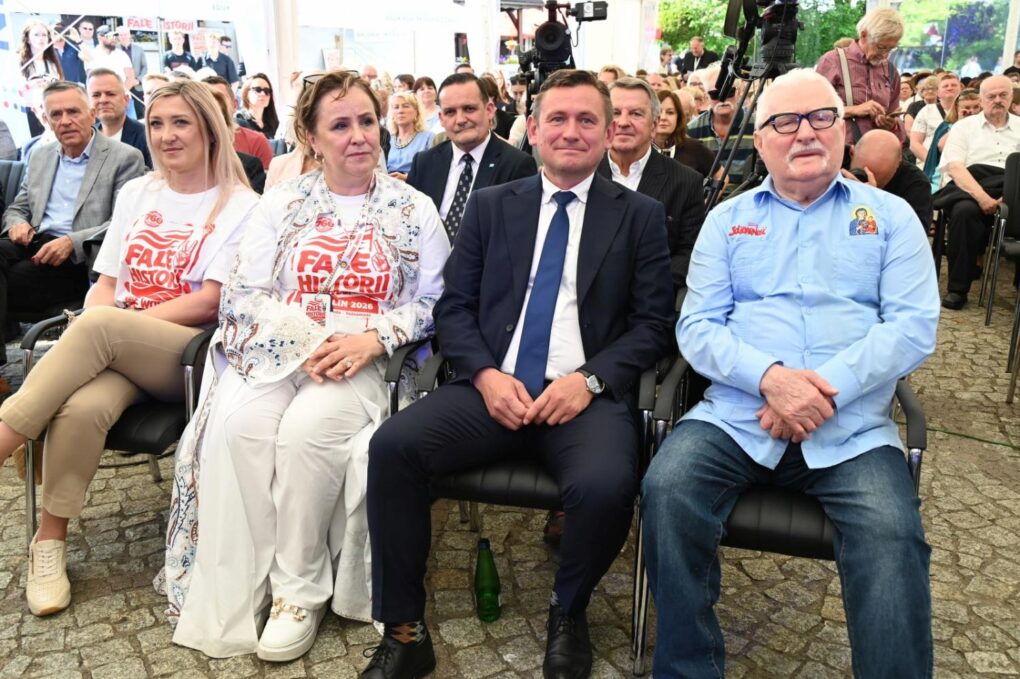 Uczestnicy i organizatorzy festiwalu „Fale Historii” siedzą w pierwszym rzędzie przed rozpoczęciem programu, a z nimi gość specjalny Lech Wałęsa, w tle liczna publiczność (kliknięcie powiększy zdjęcie).